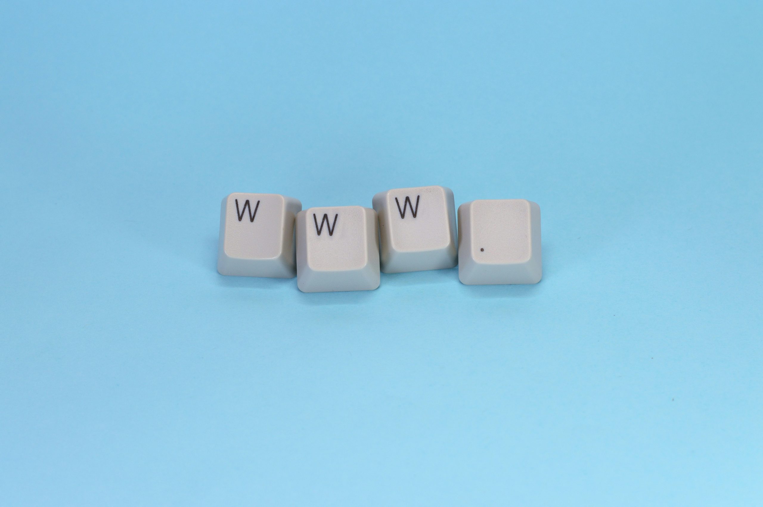 Die Zeichenfolge "www." wird durch einzelne Tastaturcaps vor einem hellblauen Hintergrund dargestellt. Das Bild ist von Miguel Angel Padrinan über Unsplash.
